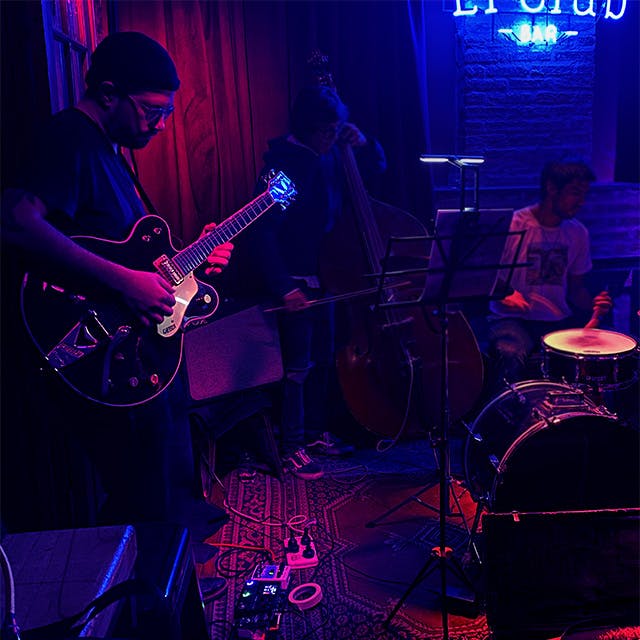 Photo de Pablo Cúbico, fondateur de VOGUM, jouant de la guitare dans un club de jazz.